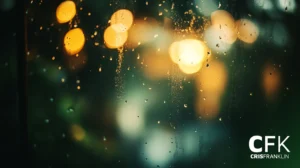 Gotas de chuva em uma janela com luzes amarelas e verdes borradas ao fundo. O texto diz "CFK CRISFRANKLIN" no canto inferior direito.
