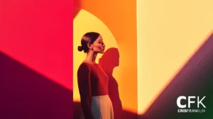 Uma mulher está de pé contra um vibrante cenário vermelho, laranja e amarelo, projetando uma sombra. O texto diz "CFK Cris Franklin" no canto.