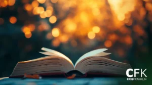 Um livro aberto repousa sobre uma superfície com luzes douradas desfocadas no fundo.