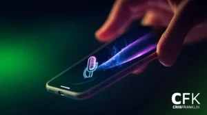 Uma mão segura um smartphone exibindo um ícone de microfone brilhante e um gráfico de onda sonora na tela, com um fundo escuro e desfocado.