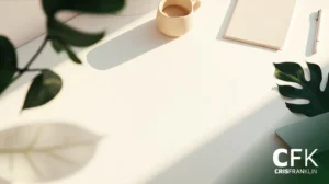 Espaço de trabalho minimalista com uma mesa branca, xícara de café, bloco de notas, laptop e folhas de plantas; a luz do sol projeta sombras sobre a superfície. Logotipo "CFK CRISFRANKLIN" no canto inferior direito.
