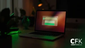 Um laptop está sobre uma mesa escura com um brilho esverdeado, exibindo uma interface de bate-papo ou de mensagens na tela. O logotipo "CFK CRISFRANKLIN" está visível no canto inferior direito.