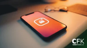 Um smartphone exibindo um ícone de aplicativo de mídia social está sobre uma mesa com um par de óculos embaçado ao fundo.